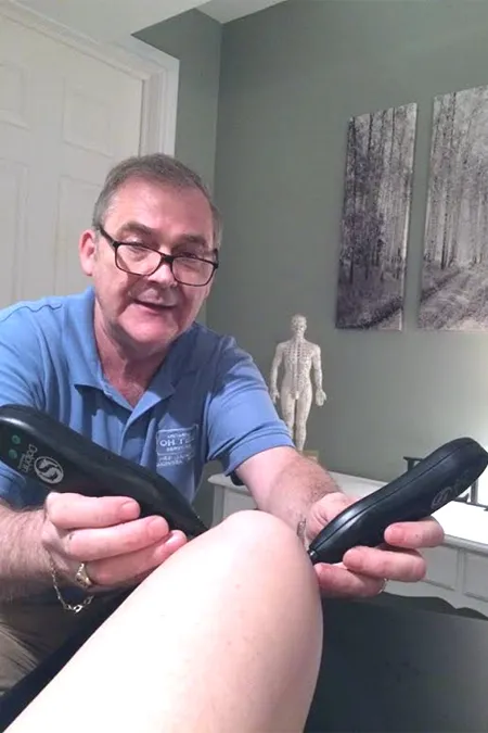 Philip providing a treatment with the Dolphin Neurostim to a persons knee.