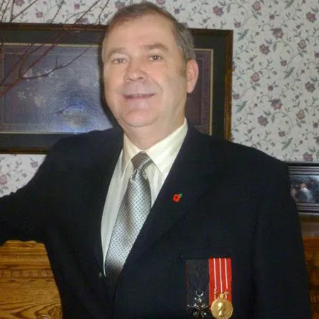 Philip standing in front of a mantle wearing a blue suit with a medal.